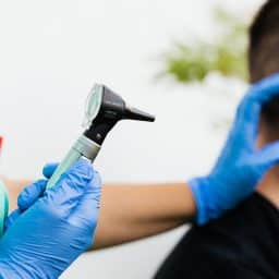 Doctor preparing to examine a man's ear for earwax buildup.
