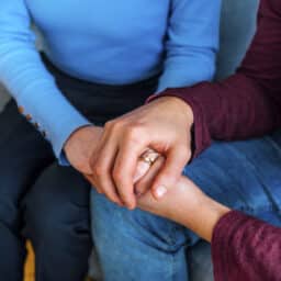 Two people holding hands, supporting each other.