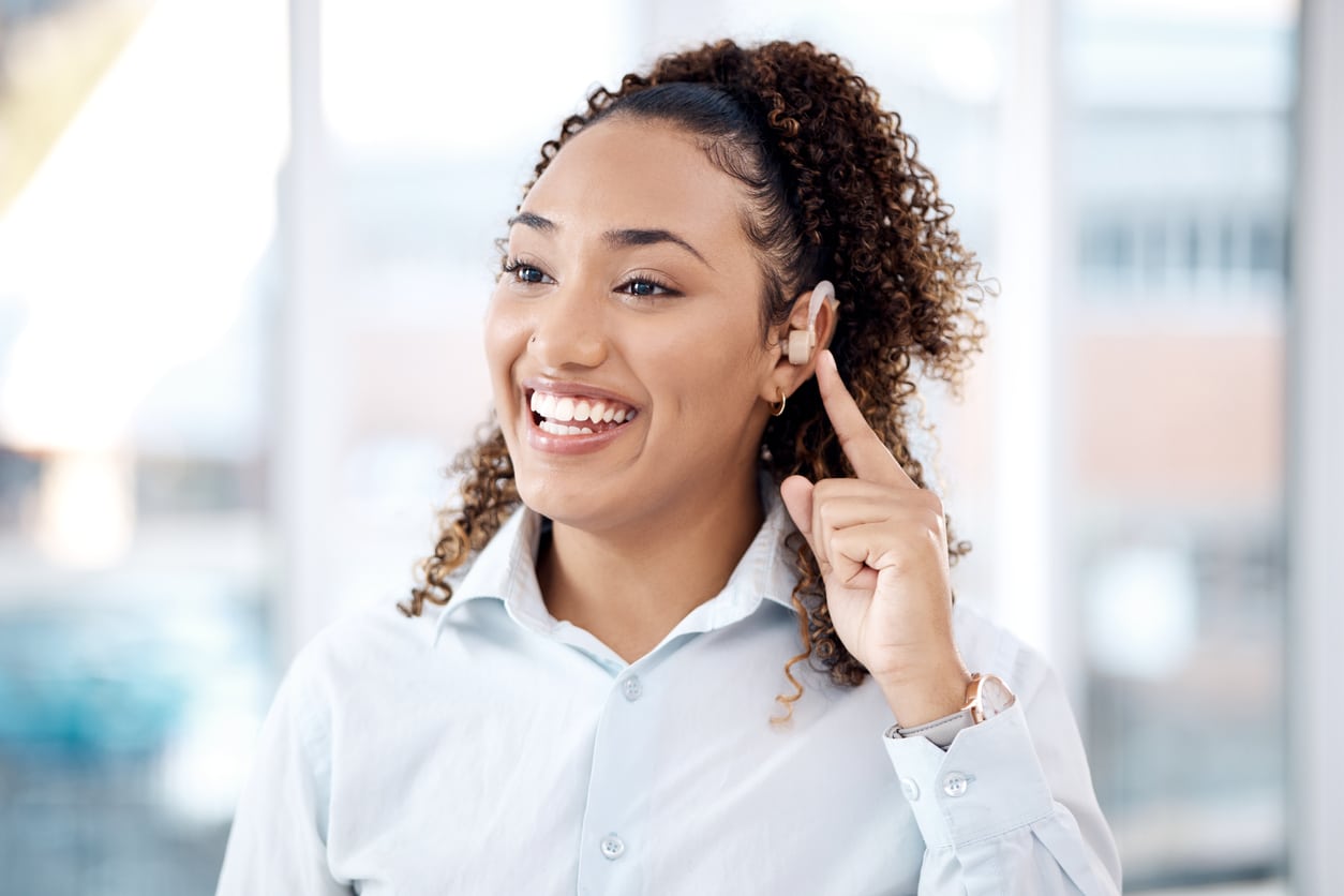 Happy woman pointing to her hearing aid.
