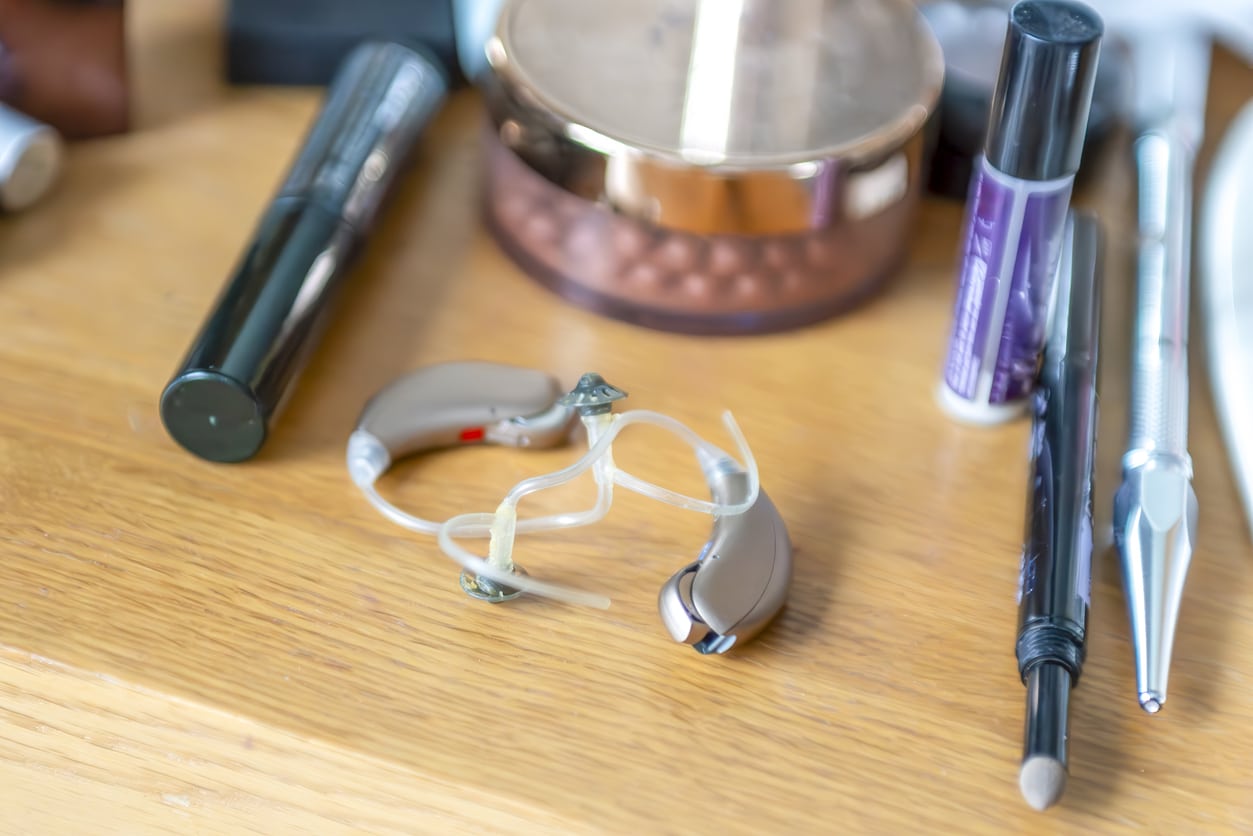 Hearing aids sitting on a table with makeup supplies.