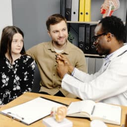 Doctor showing a young girl how to use her hearing aid