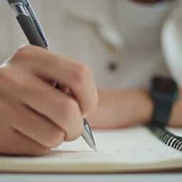 CLose-up of someone taking notes in a journal prior to a hearing appointment.