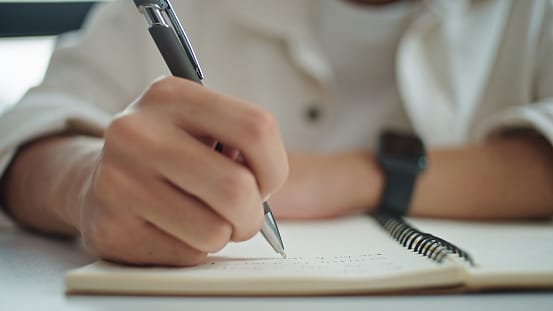CLose-up of someone taking notes in a journal prior to a hearing appointment.