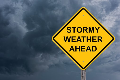 Road sign reading "STORMY WEATHER AHEAD" with a stormy sky behind