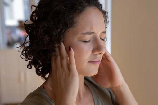 Distressed person with tinnitus covering her ears