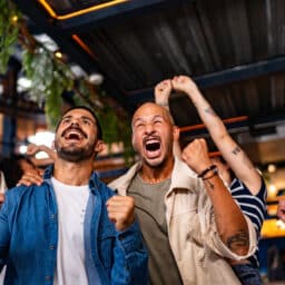Friends watching sports and celebrating at bar